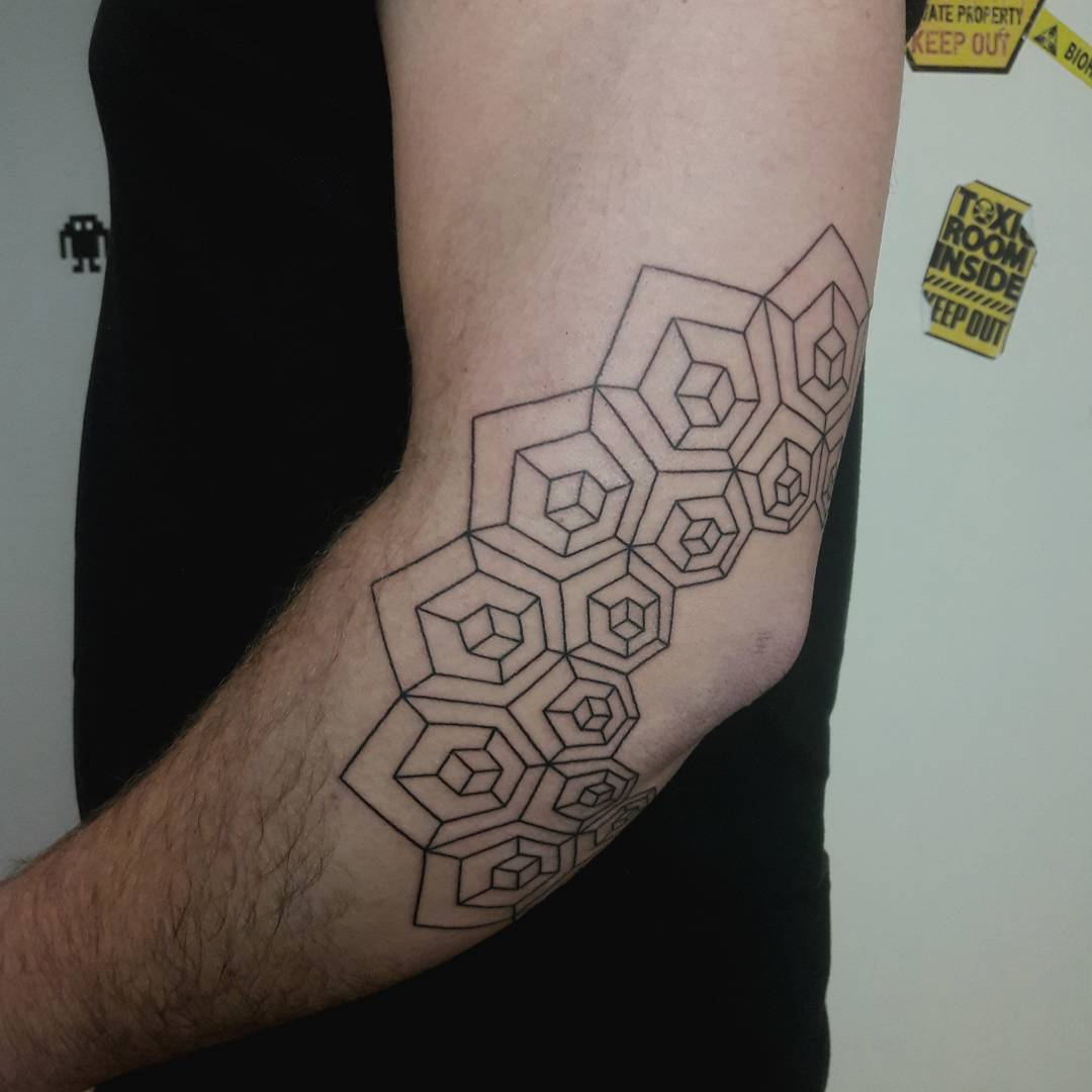 Geometric mandala tattoo around the left elbow
