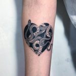 Heart-shaped snakes tattoo on the forearm
