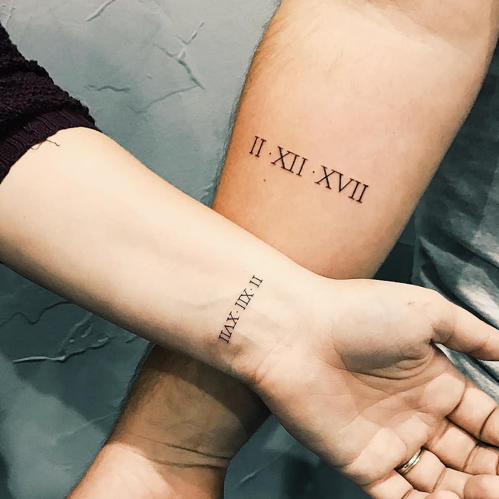 Matching Roman numerals date tattoos by Cholo Related Tattoos.