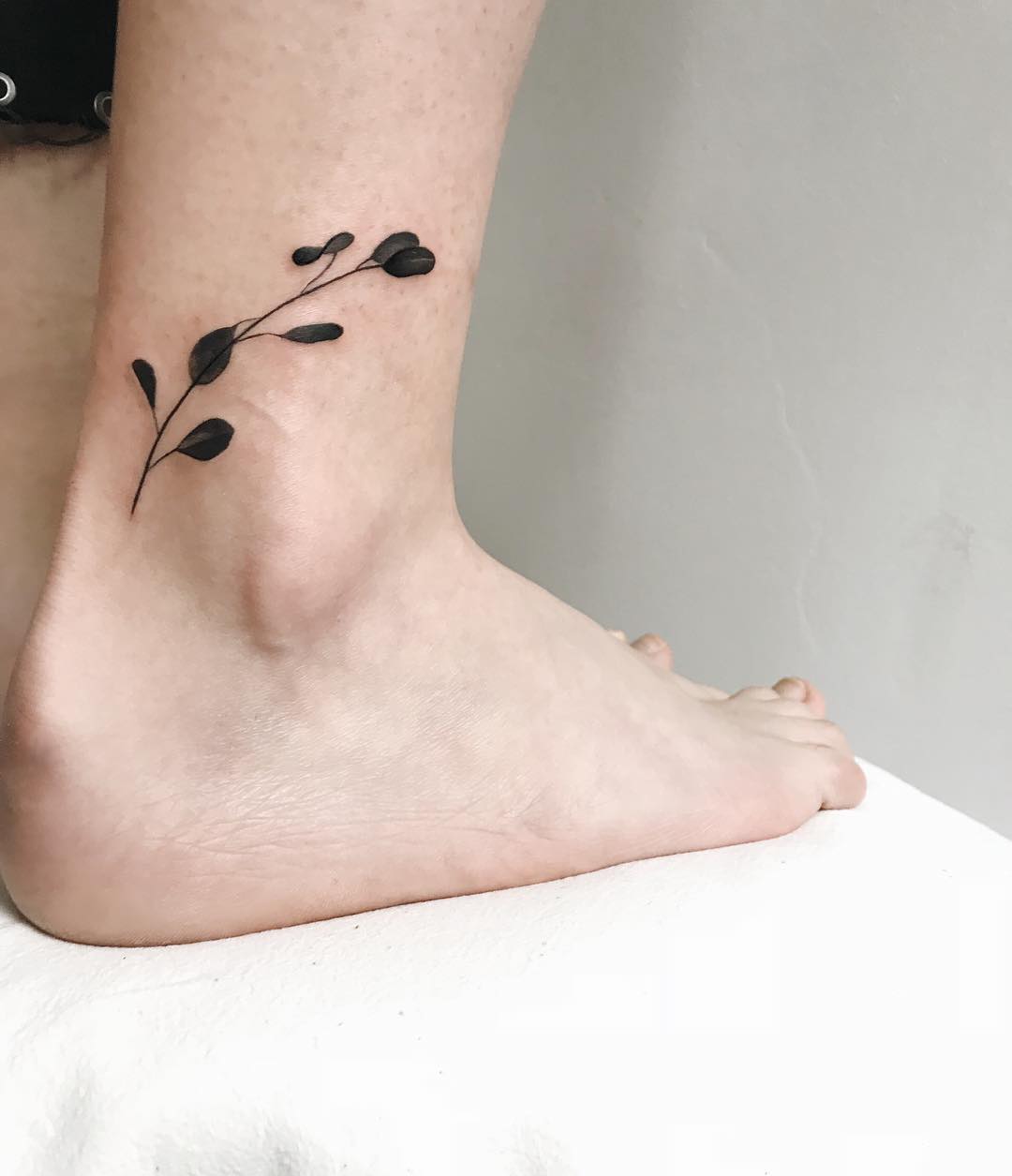 Solid black plant tattoo on the ankle