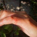 Tiny hand-poked ribbon tattoo