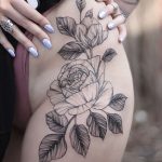 Black and grey rose tattoo on the hip