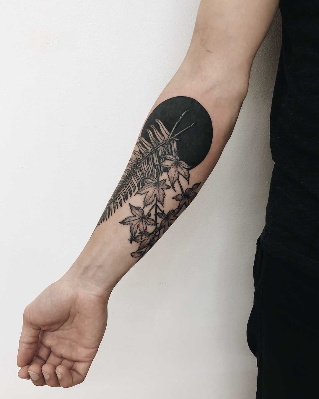 Fern leaf and black circle tattoo by Finley Jordan