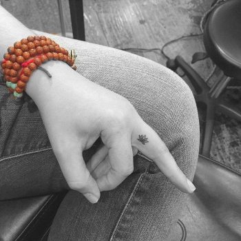 Tiny Lotus tattoo on a finger