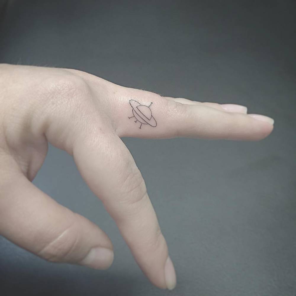 Tiny UFO tattoo on the middle finger
