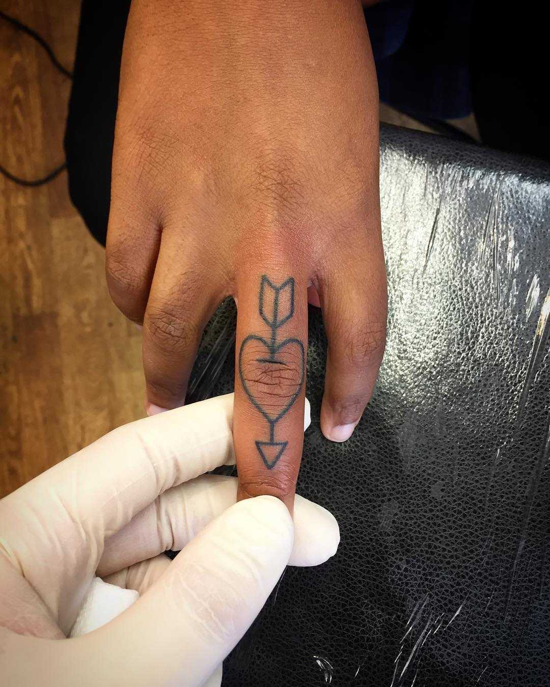 Arrow and heart finger tattoo by Kirk Budden