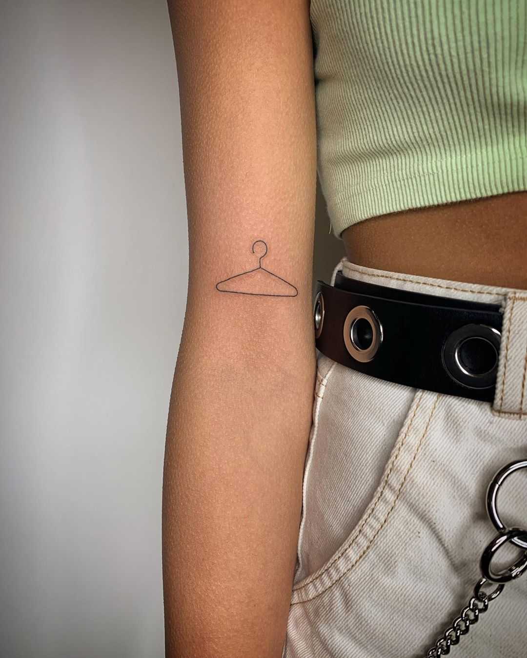 Hand-poked little coat hanger tattoo by Kirk Budden