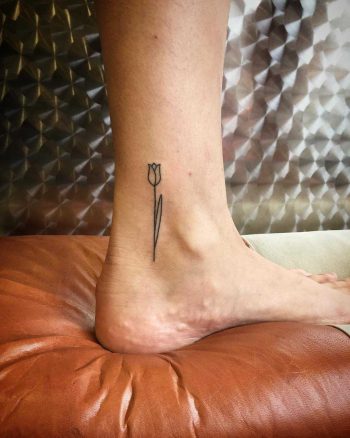 Little tulip tattoo on an ankle by Kirk Budden