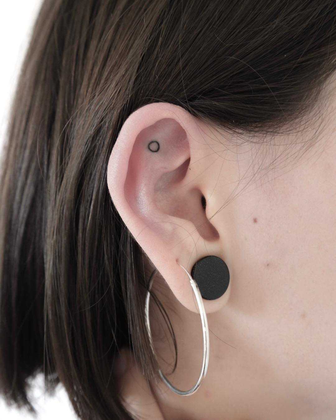 Tiny circle tattoo on the ear by Ann Gilberg