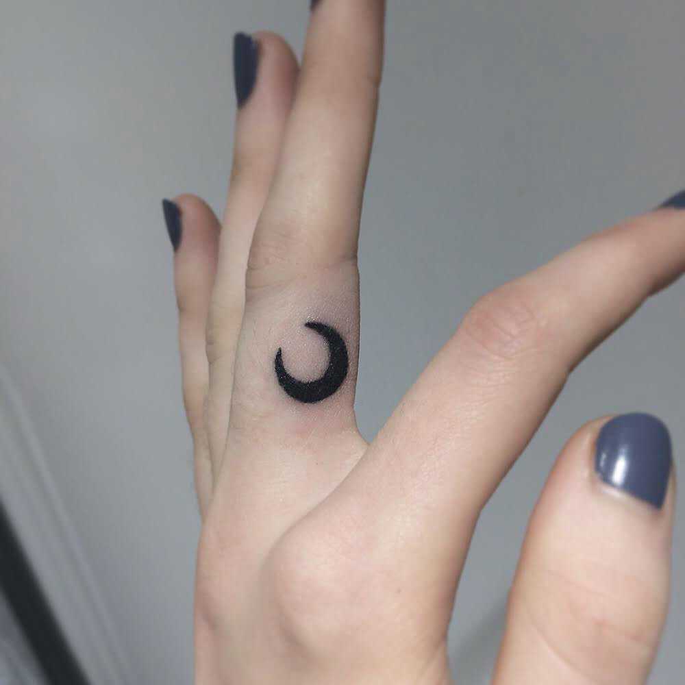Tiny crescent moon tattoo by Kirk Budden