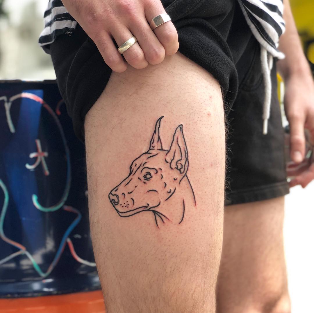 Dog on a thigh by Hand Job Tattoo