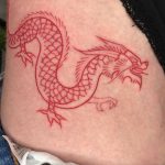 Red dragon tattoo on a hip by Loz Thomas