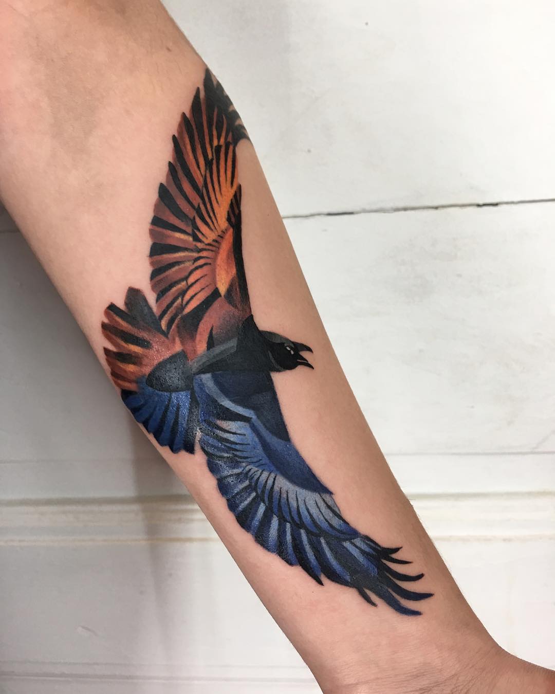 A flame colored raven tattoo by Mavka Leesova