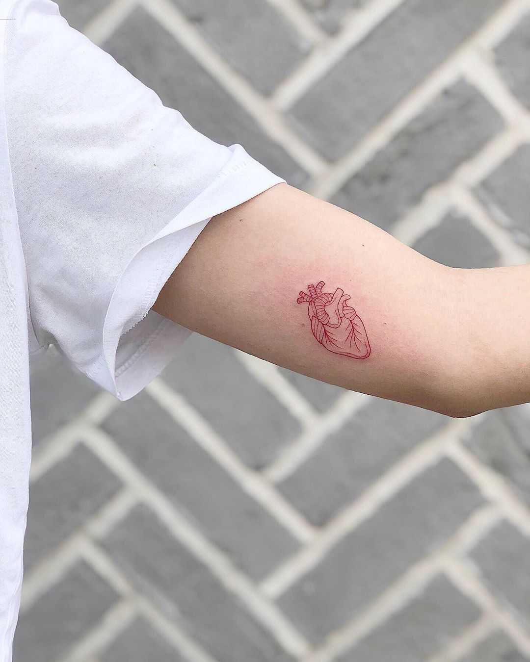 Tiny red heart tattoo by Loz Thomas