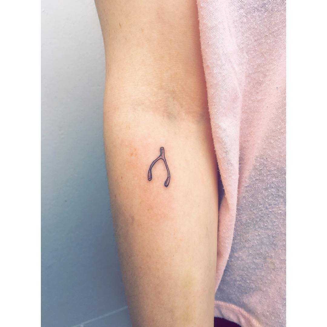 Tiny wishbone tattoo by Zaya Hastra