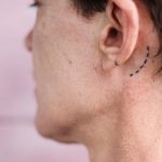 Dashed line tattoo behind the left ear by Stanislava Pinchuk