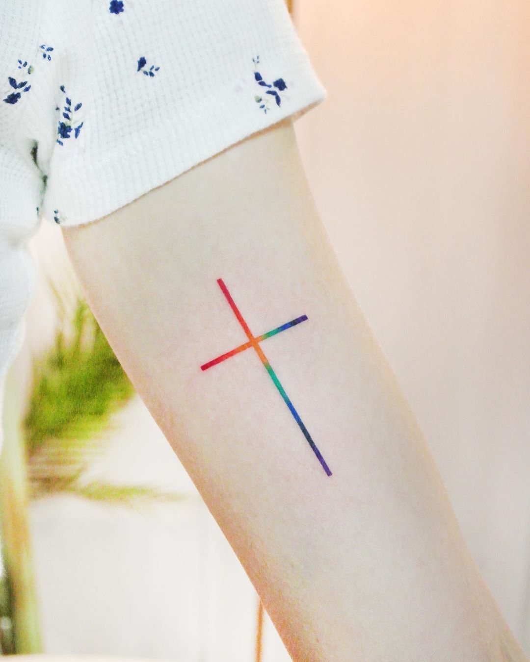 Watercolor rainbow cross by tattooist Cozy Related Tattoos.