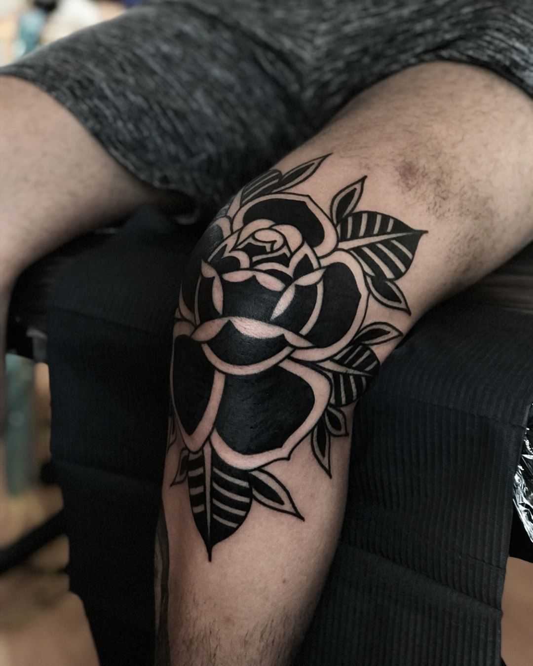 Black rose on a knee by tattooist Alejo GMZ
