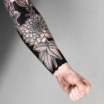 Negative space floral forearm piece by tattooist MAIC